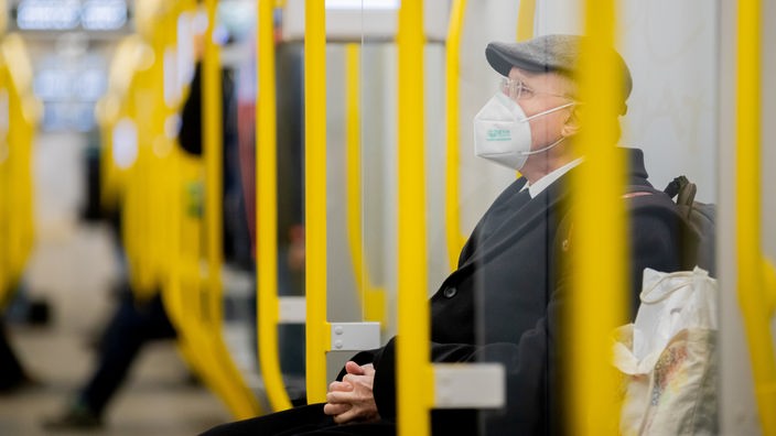 Mann mit FFP2-Maske sitzt in einer Straßenbahn