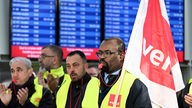 Streikende Flughafen-Mitarbeiter stehen mit Verdi-Flaggen im Terminal des Flughafens.