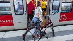 Eine Frau steigt mit ihrem Fahrrad in einen Regionalzug ein