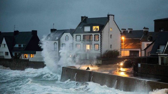 Wellen peitschen gegen eine Hausfassade während eines Sturmes in der Bretagne