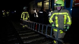 Feuerwehrleute am Unfallort - im Hintergrund die Regionalbahn