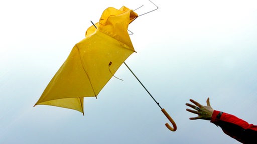 Gelber Regenschirm fliegt aus der Hand