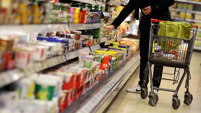 Eine Person greift eine Butter aus dem Kühlregal in einem Supermarkt - Archiv