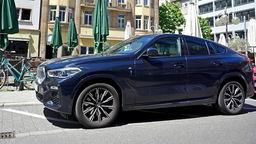Ein dunkelblauer SUV der Marke BMW steht an einer Straße