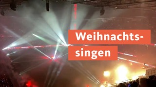 Tausende singen in einem Stadion in Köln zusammen Weihnachtslieder