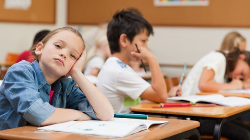 Gelangweilte Schüler bei Frontalunterricht im Klassenraum