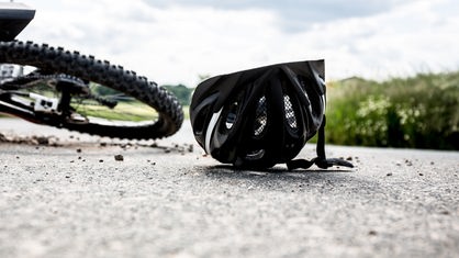 Fahrrad und Helm liegen nach einem Unfall auf der Straße