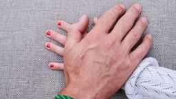 Eine Männerhand liegt auf einer Mädchenhand (gestellte Szene)