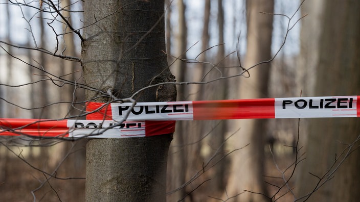 Absperrband der Polizei sperrt einen Tatort im Wald ab