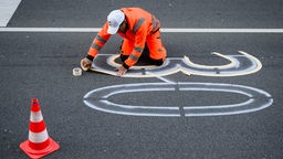 Ein Straßenarbeiter zeichnet eine 30 auf eine Fahrbahn
