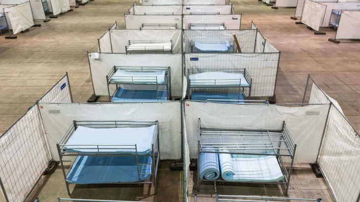 Stockbetten stehen zwischen Zäunen in einer Notunterkunft für Asylsuchende in der Messe Offenburg.