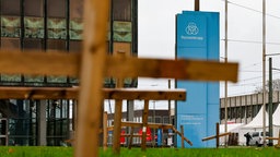 Duisburg: Holzkreuze stehen vor dem Verwaltungsgebäude von Thyssenkrupp Steel in Duisburg auf einer Wiese