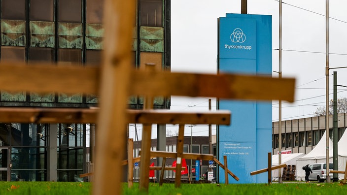 Duisburg: Holzkreuze stehen vor dem Verwaltungsgebäude von Thyssenkrupp Steel in Duisburg auf einer Wiese