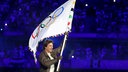 Schauspieler Tom Cruise hält bei der Abschlussfeier in Paris eine Fahne mit den olympischen Ringen.