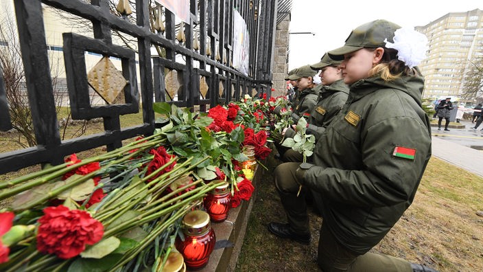 Trauernde in Moskau vor Rosen an einem Zaun