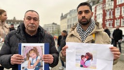 Trauermarsch in Solingen - Zwei Männer halten Bilder der Opfer 