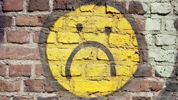 Trauriger Smiley auf eine Backsteinmauer gemalt