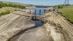 12.08.2022, Großbritannien, Ripponden: Trockene, rissige Erde ist am Baitings Reservoir zu sehen, wo der Wasserstand sehr niedrig ist