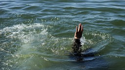 Illustration: Ertrinkende Person hält die Hand aus dem Wasser hoch