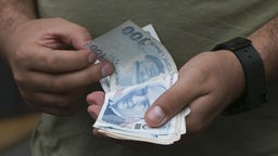 Ein Mann zählt Geldscheine (Türkische Lira)