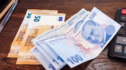 100-Lira-Geldscheine, Euro-Banknoten und ein Taschenrechner liegen auf einem Tisch