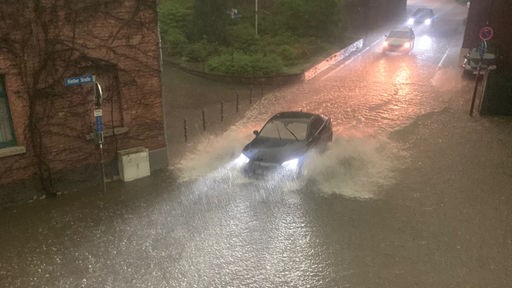 Ein Auto fährt durch knietiefes Wasser