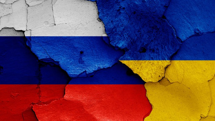 Symbolbild: Zerbröckelnder Putz in den Nationalfarben Russlands und der Ukraine