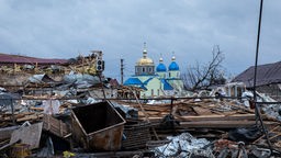 Ukraine, Byschiw: Durch Beschuss des russischen Militärs zerstörte Gebäude liegen in Trümmern und machen den Blick auf eine noch intakte orthodoxe Kirche in Byschiw, einem Vorort von Kiew, möglich.