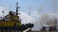 Ukrainische Feuerwehrleute kämpfen gegen ein Feuer auf einem Boot, das im Hafen von Odessa brannte, nachdem Raketen den Hafen getroffen hatten