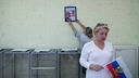 Ein Mitglied der Wahlkommission hängt in Vorbereitung auf das "Referendum" ein Bild des russischen Präsidenten Putin auf