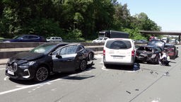 Eine Unfallstell auf der Autobahn mit vier Autos, daneben hockt ein Polizist.