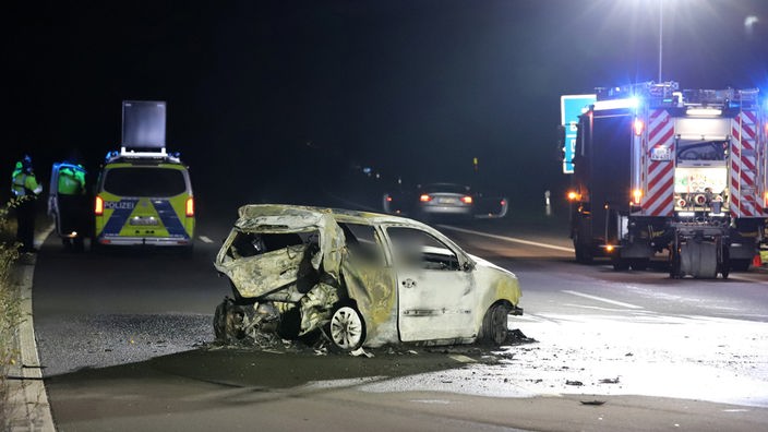 Ein ausgebranntes Auto steht auf der A555, Polizei und Feierwehr am Einsatzort