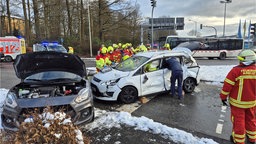 Feuerwehr befreit Personen aus einem weißen Pkw, die durch die Kollision eines Linienbusses mit einem Pkw in Kreuztal verletzt wurden.