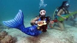Muiskerin unter Wasser mit Instrument und Meerjungsfrauenkostüm