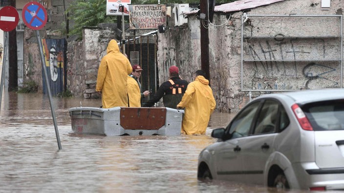 Menschen und ein Auto auf einer gefluteten Straße in Volos