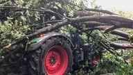 Ein dicker Baum ist auf einen Traktor gestürzt. Eine Gewitterfront hat am Donnerstagabend im Rheinland Schäden verursacht.