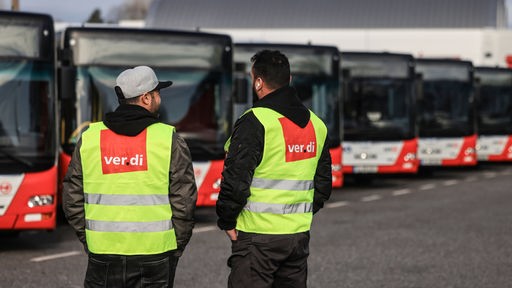 Gewerkschaftsmitglieder von Verdi stehen beim Warnstreik am 29.02.2024 bei den Kölner Verkehrsbetriebe KVB vor abgestellten Bussen.