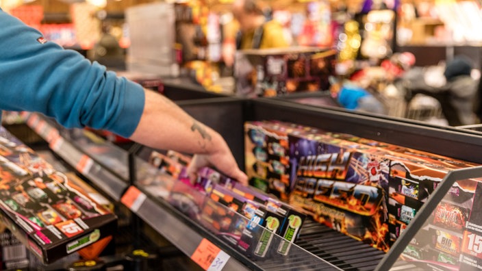 Ein Kunde eines Supermarktes nimmt Feuerwerk aus einem Regal