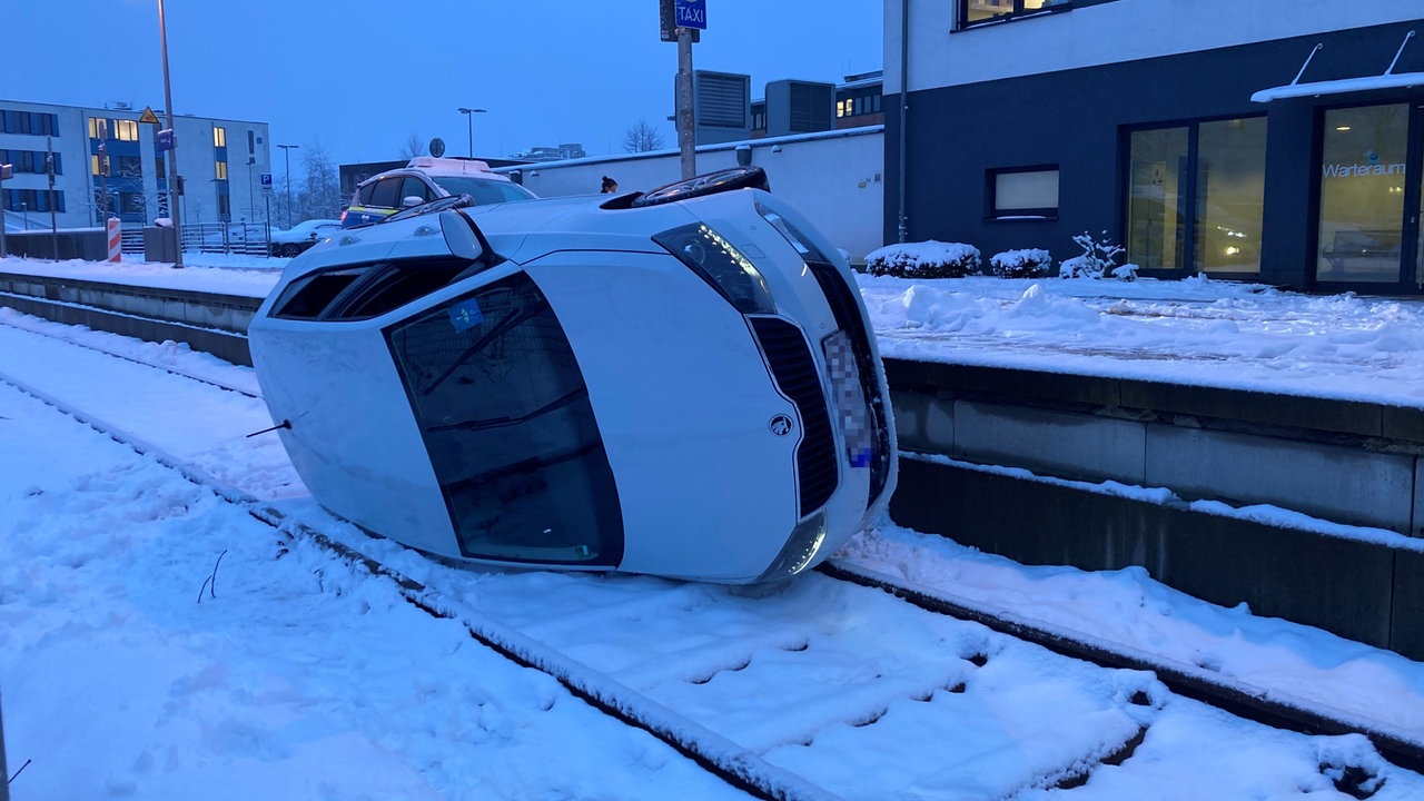 Ein Auto liegt auf der Seite neben der Straße auf einem Gleis