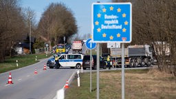 Ein Polizeiwagen blockiert zur Kontrolle eine Straße zur Grenze nach Deutschland.