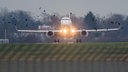 Ein Flugzeug landet am Flughafen Hannover, als ein Vogelschwarm vorüberfliegt