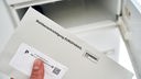 Hand holt einen Brief mit der Wahlbenachrichtigung zur Europawahl 2024 aus dem Briefkasten
