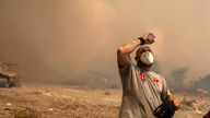 Mann mit Wasserflasche in den Waldbrändne in Griechenland
