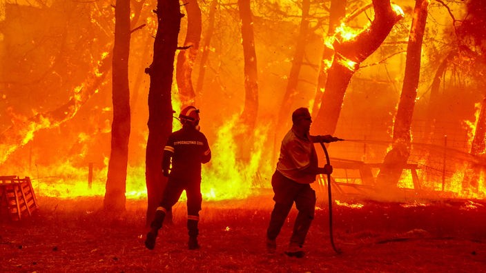  Ein Feuerwehrmann und ein Freiwilliger versuchen Flammen eines Waldbrandes in der Nähe des Badeortes Vetera zu löschen. 