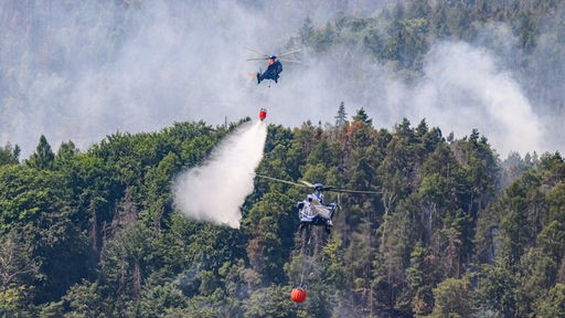Hubschrauber der Bundespolizei fliegen mit einem Löschwasser-Außenlastbehälter um einen Waldbrand im Nationalpark Sächsische Schweiz zu löschen