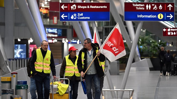 Streikende Flughafenmitarbeiter gehen durch das Terminal.