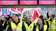 Streikende Flughafen-Mitarbeiter stehen mit Verdi-Flaggen im Terminal des Flughafens