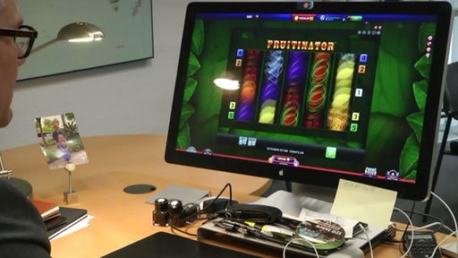 Mann sitzt vor einem PC, Online-Glücksspiel auf dem Bildschirm
