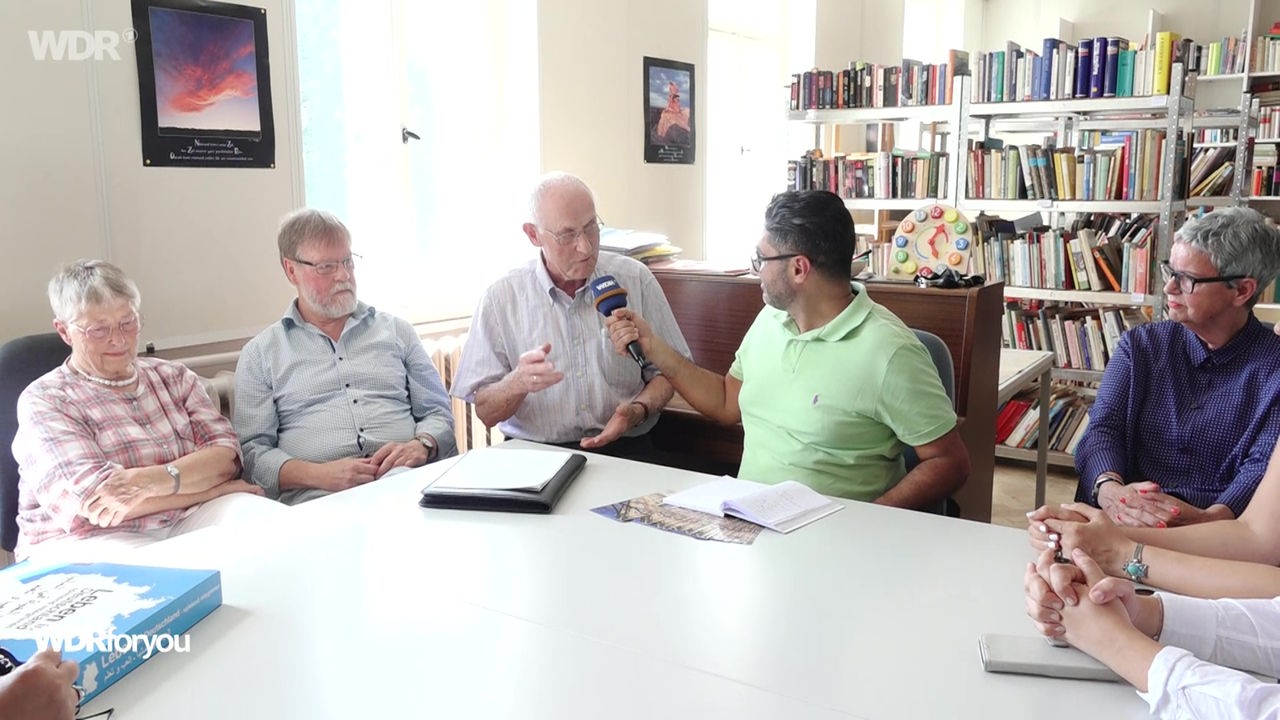 Ehrenamtliche Helfer und Flüchtlinge vom Cafe Gustav sprechen mit Bamdad Esmaili
