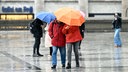 Spaziergänger gehen am Dom-Vorplatz mit Schirmen durch den Regen